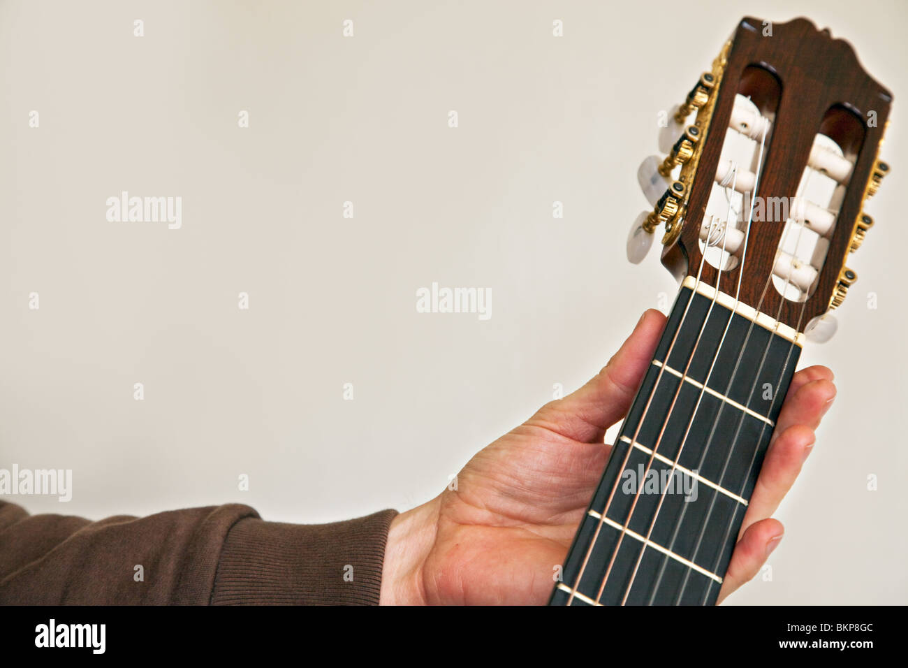 Nylon string classical guitar close up with left hand holding the fretboard neck Stock Photo