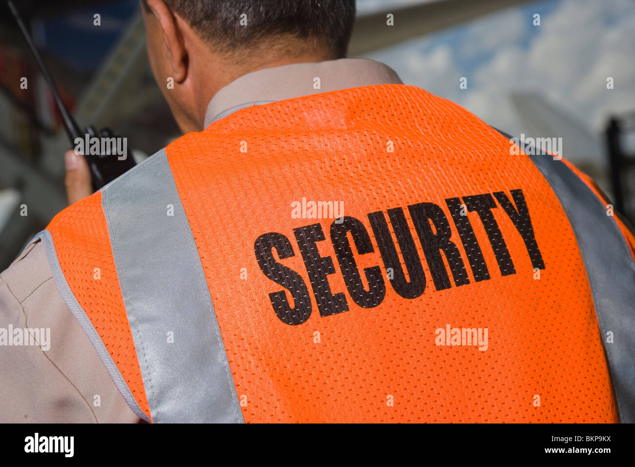 Security officer with walkie talkie radio in airport, back view Stock