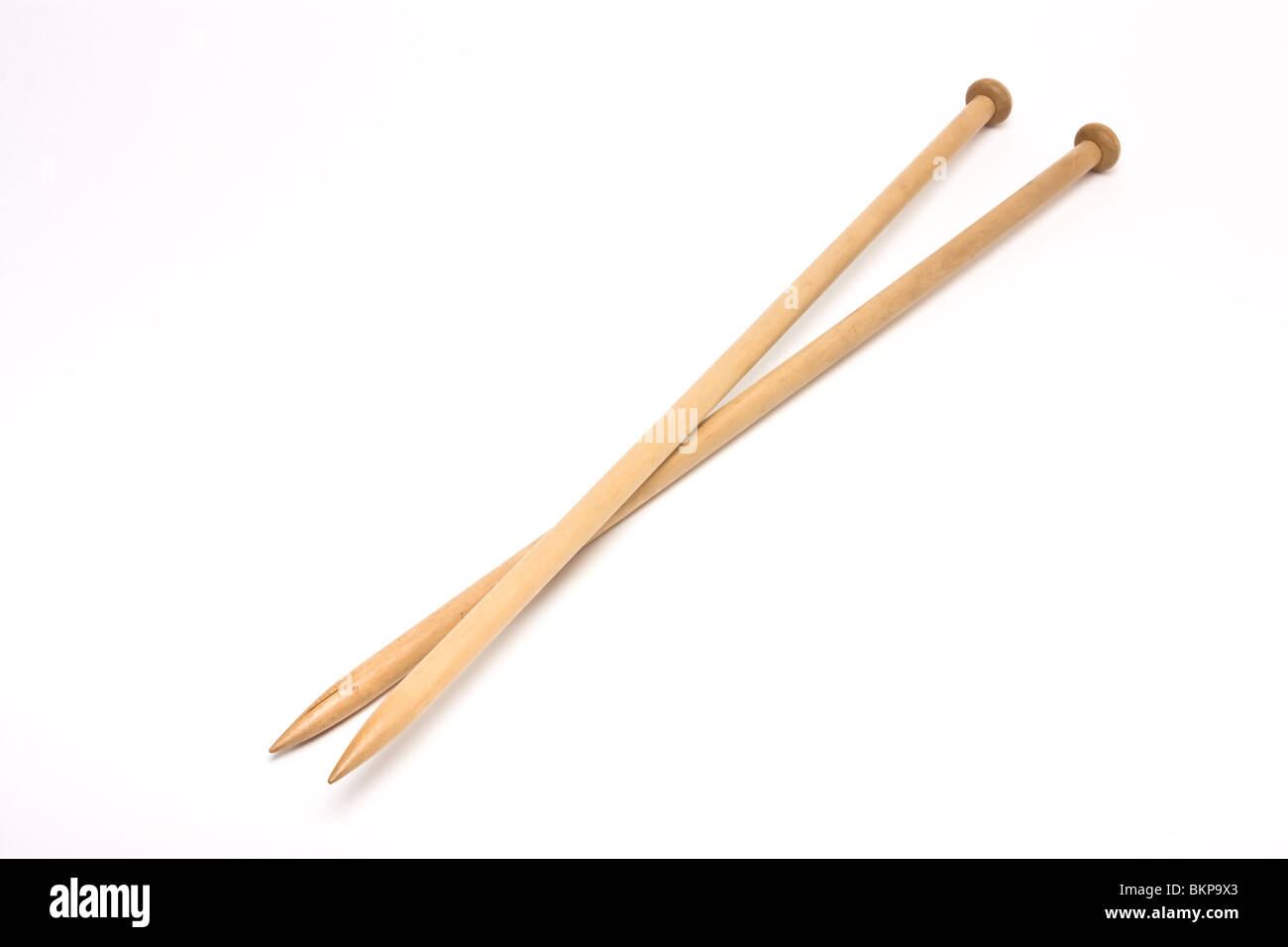 A pair of large wooden knitting needles from low perspective isolated
