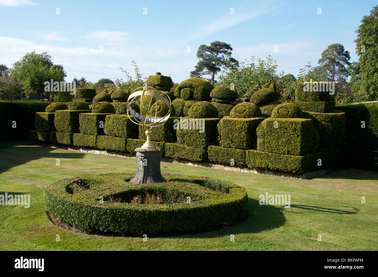 A sun dial in a formal garden with hedging in the background Stock Photo