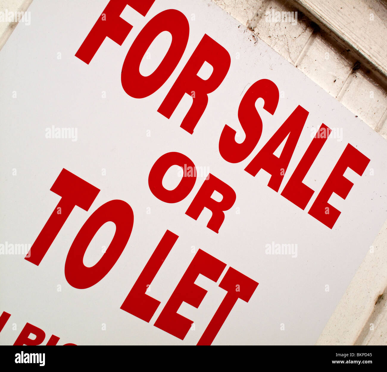 For Sale or To Let sign with red letters against a white background outside an empty commercial property Stock Photo