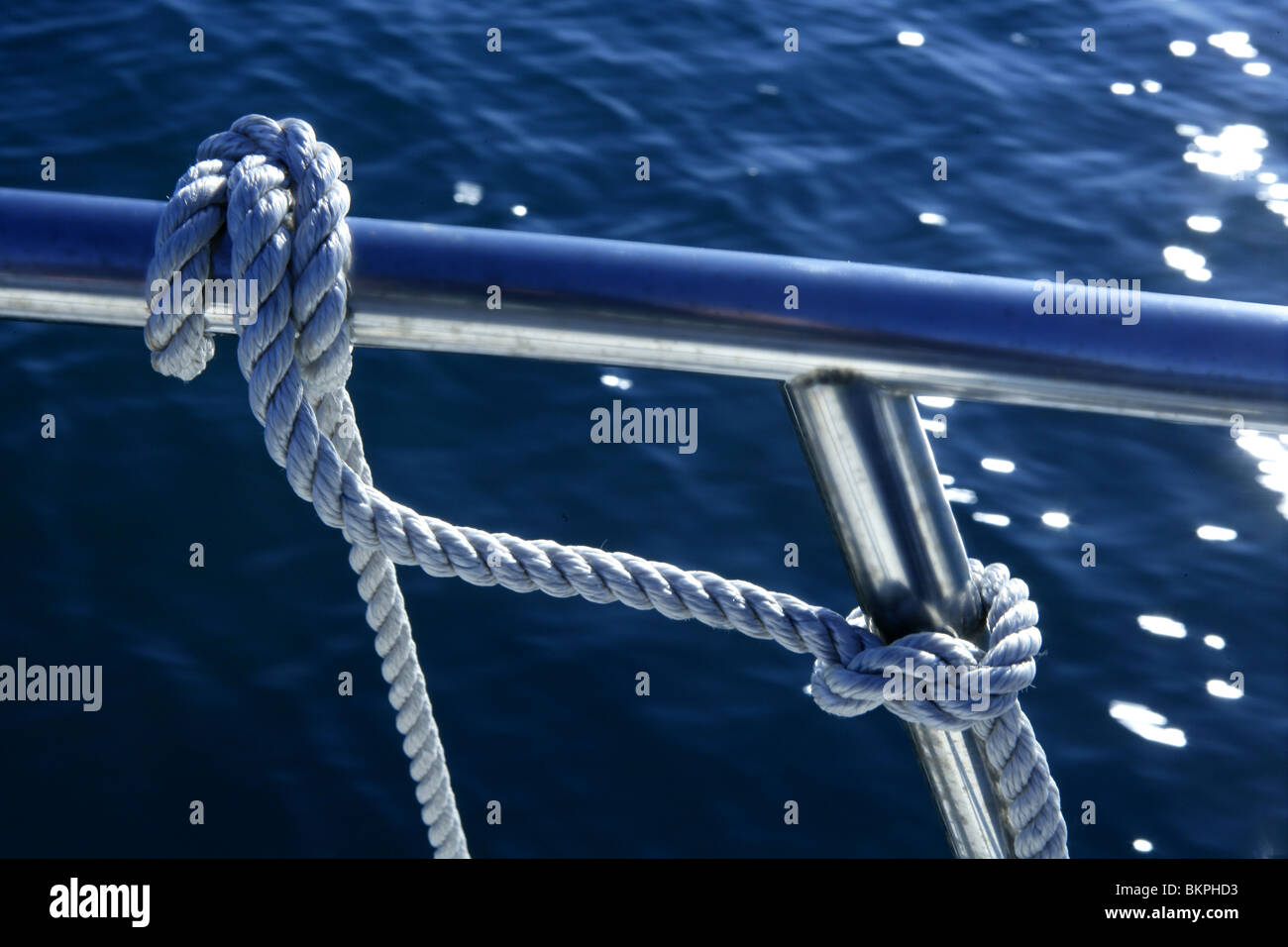 Nautical marine fender knot around stainless steel lee on blue ocean