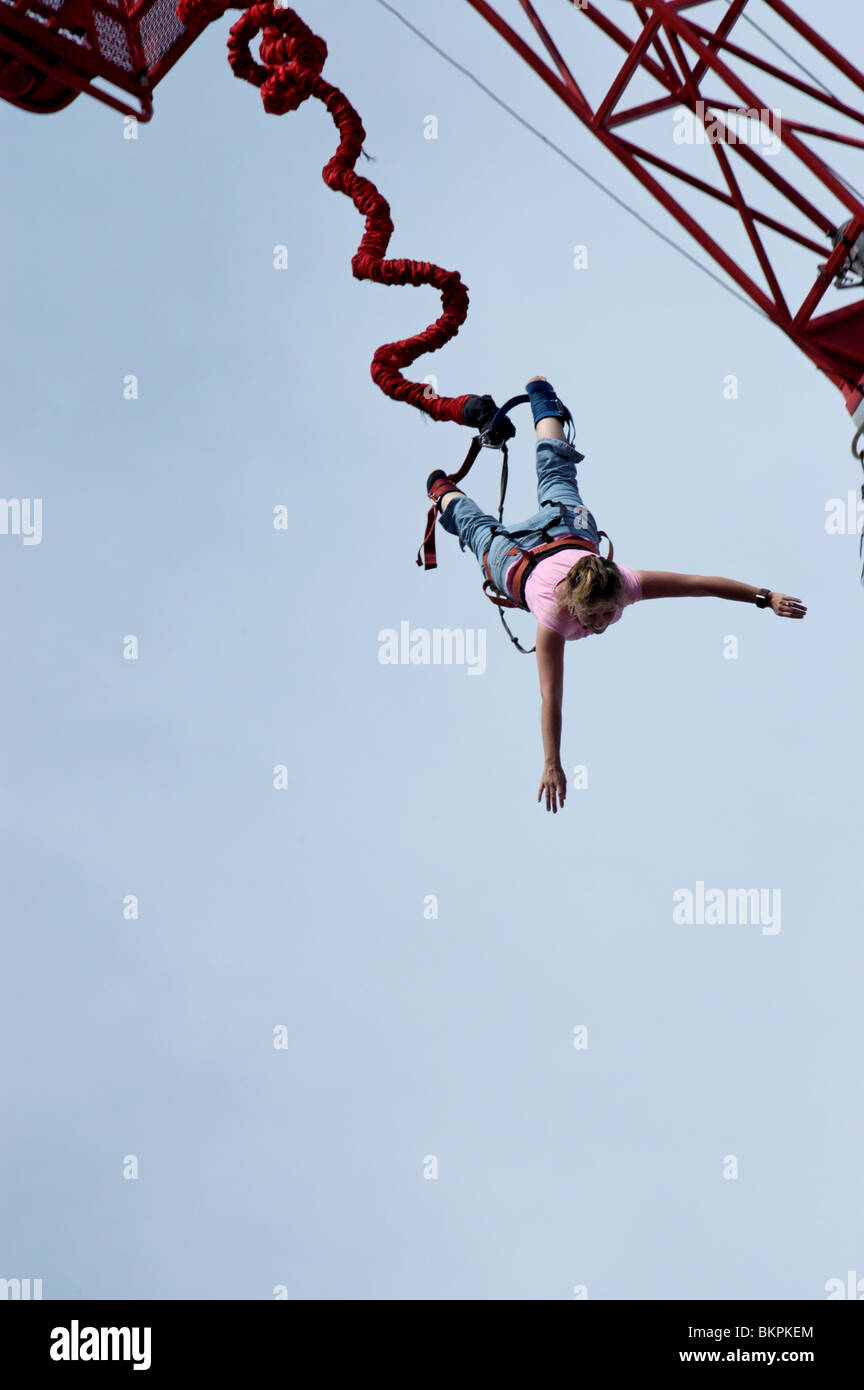 Stock photograph of a woman bungee jumping head first from a crane at