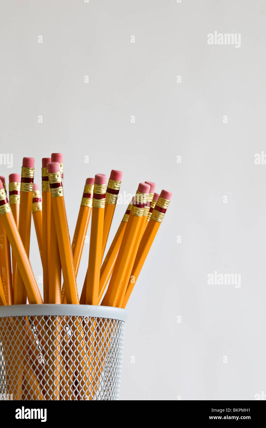 Numerous orange HB lead pencils in holder, on white background. Stock Photo