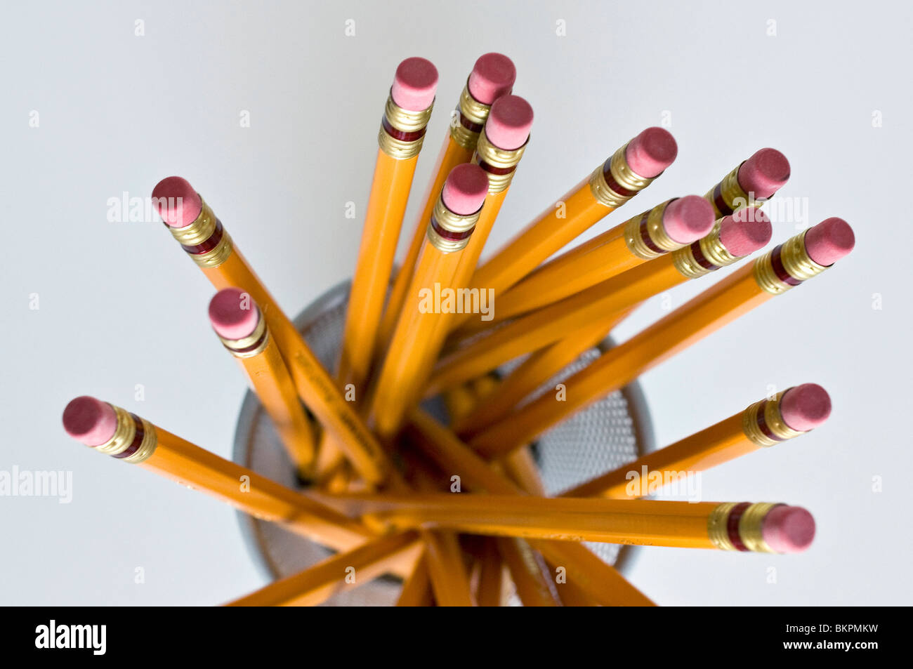 Numerous orange HB lead pencils in holder, on white background. Stock Photo