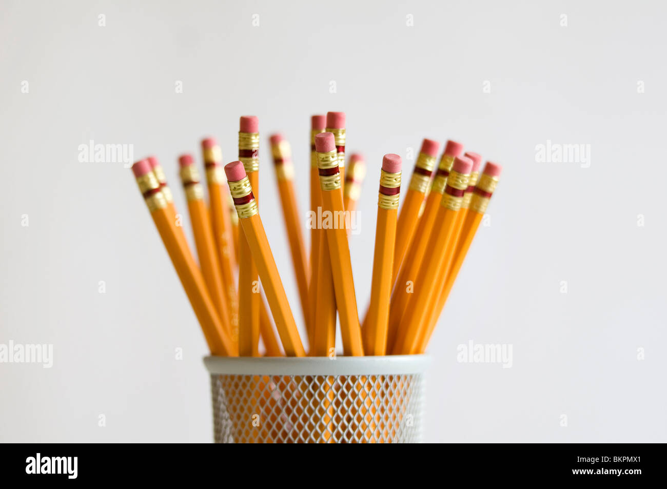 Numerous orange HB lead pencils in holder, on white background Stock