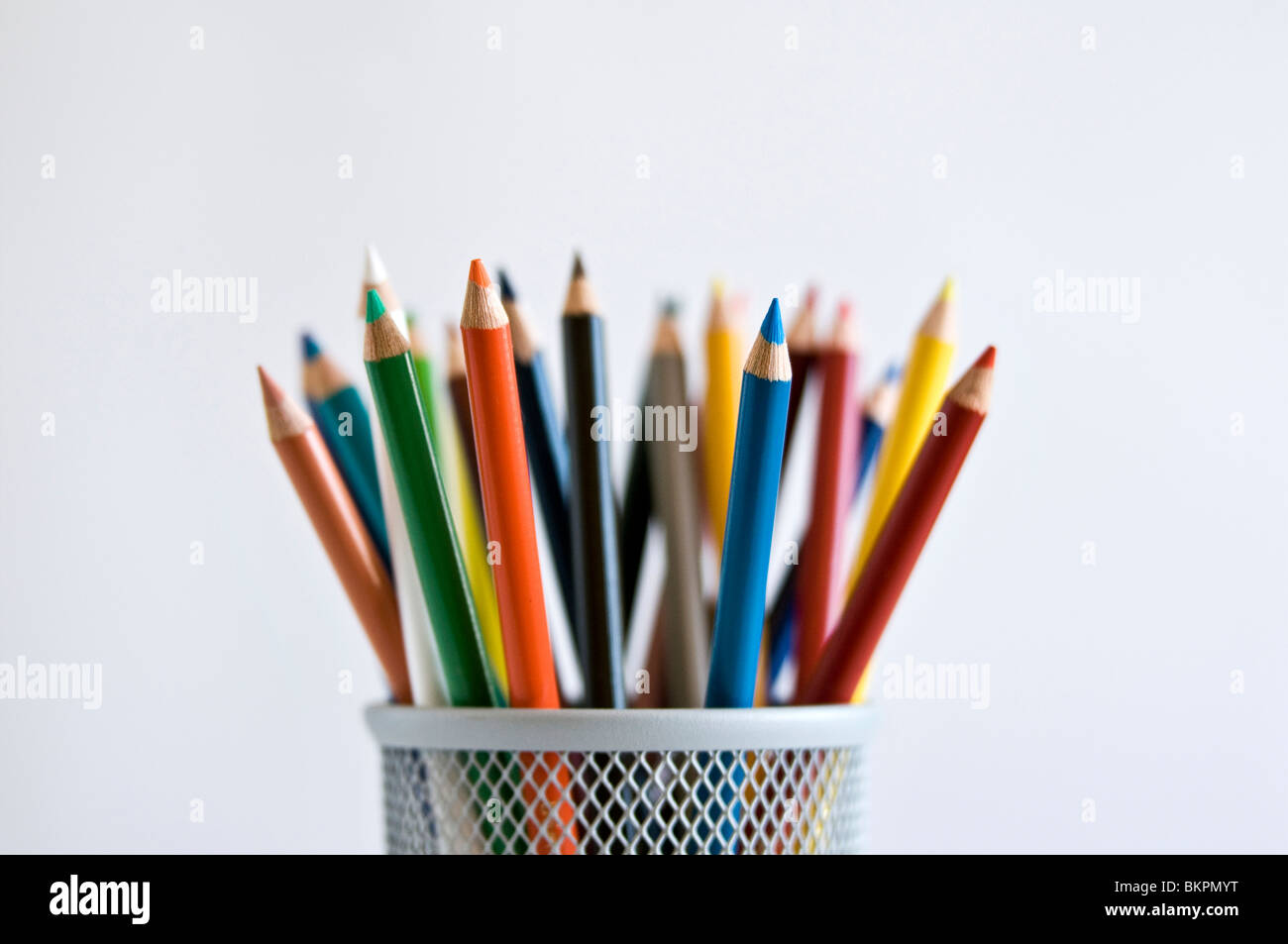 Colored art pencils in pencil holder, on white background. Stock Photo