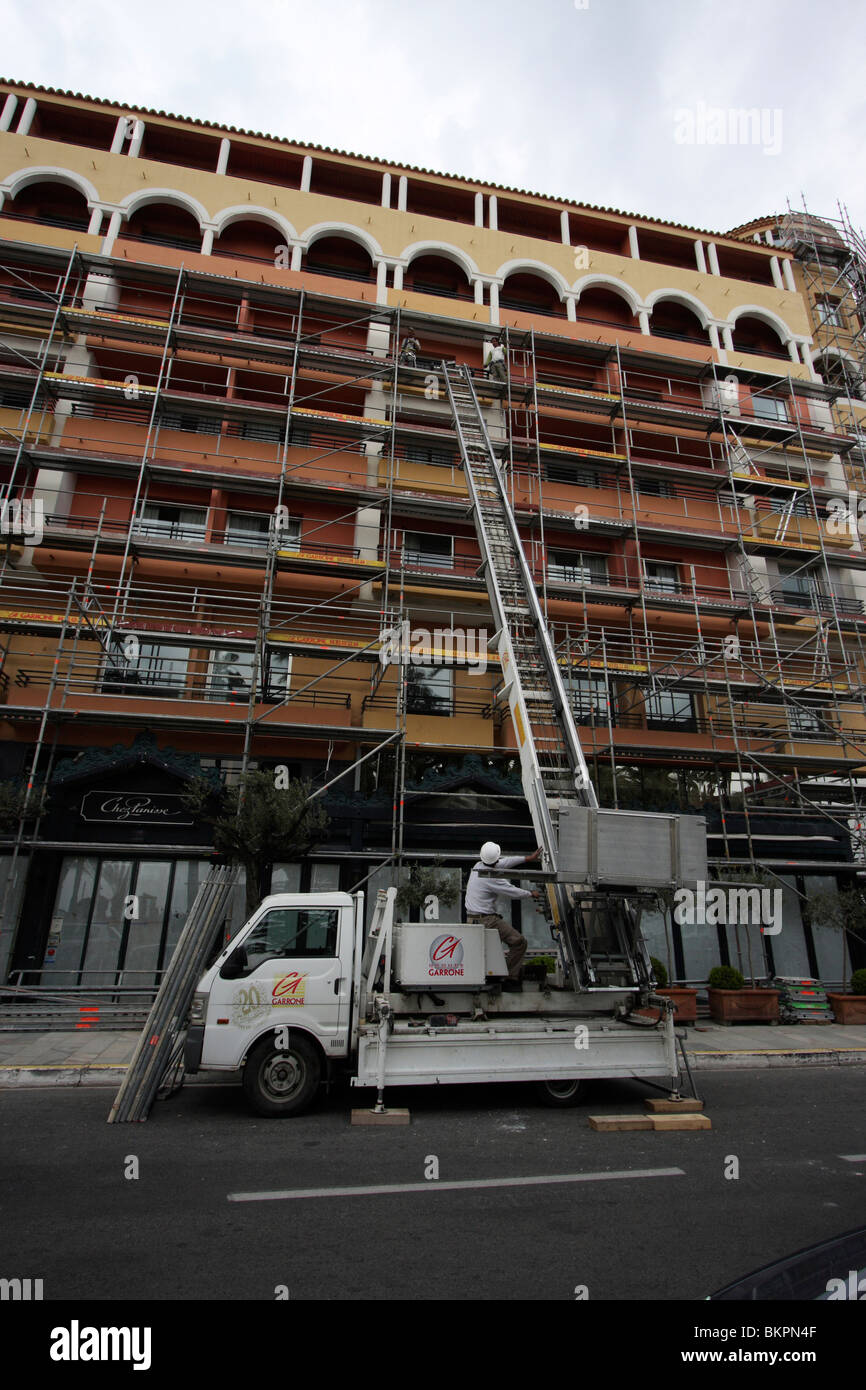 image of workers working on a multistoried building with scaffoldings and a mobile ladder truck,cannes france Stock Photo