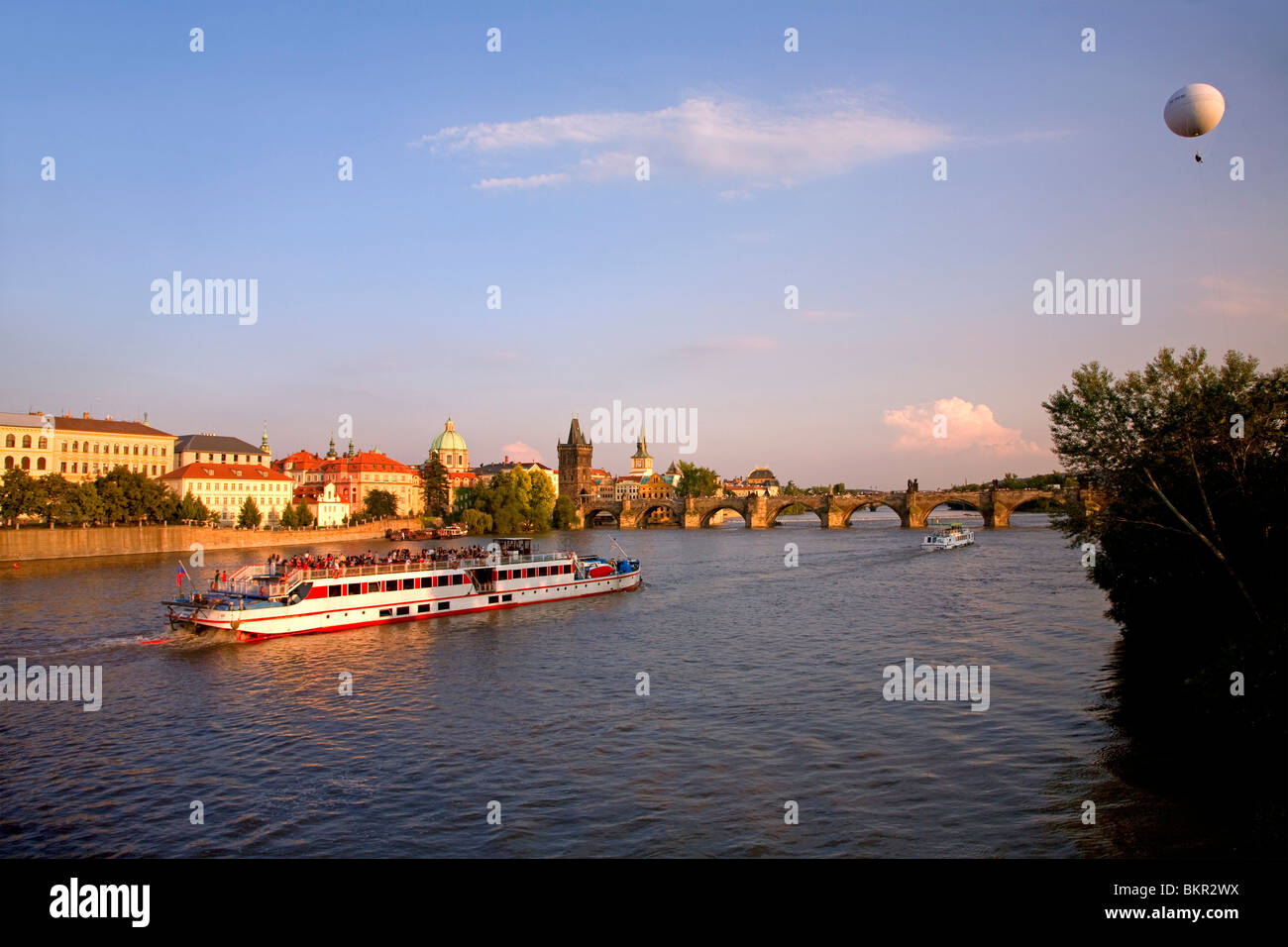Czech Republic, Prague; A boat crossing the river Vltava and a cloudhopper viewing the city below. Stock Photo