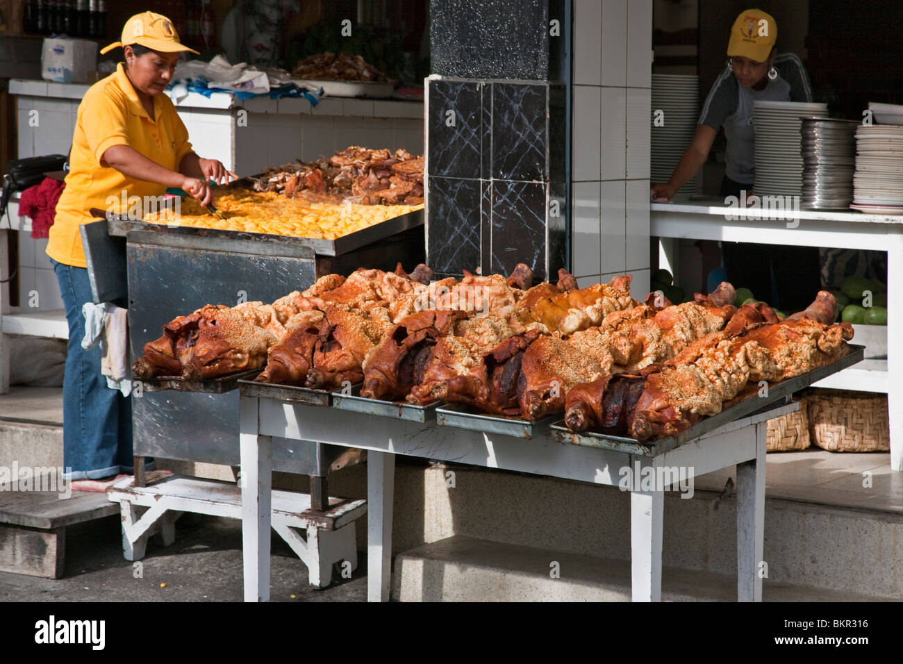 Ecuador, Roast suckling pigs on display at an open-air foodstall at Sangolqui market. Stock Photo