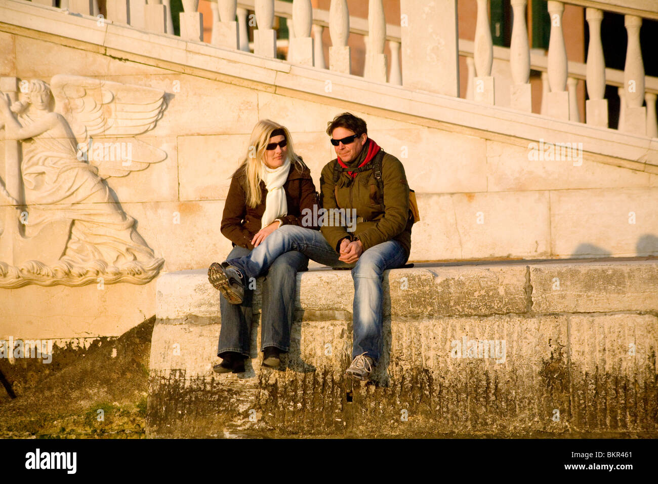 Italy, Veneto, Venice; A couple enjoying the view in front of the bridge of the Riva San Biago facing the Canale San Marco Stock Photo