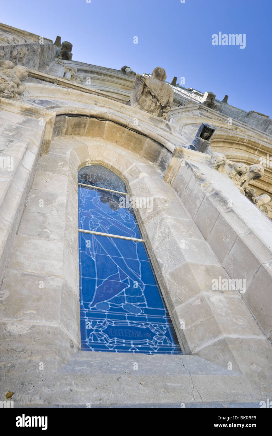 Looking up at an old church, focusing on a stained glass window, from