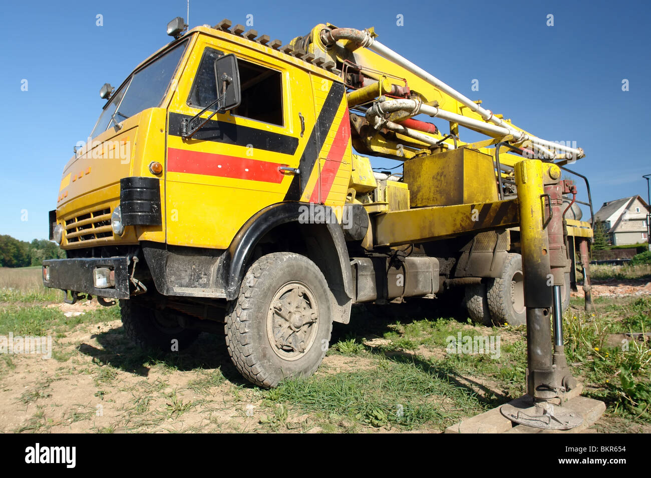 Yellow concrete mix pump truck parked at construction site Stock Photo