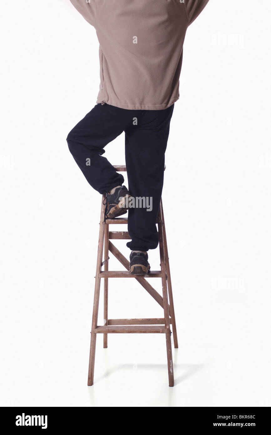Rear view of man on ladder reaching up. Isolated. Stock Photo