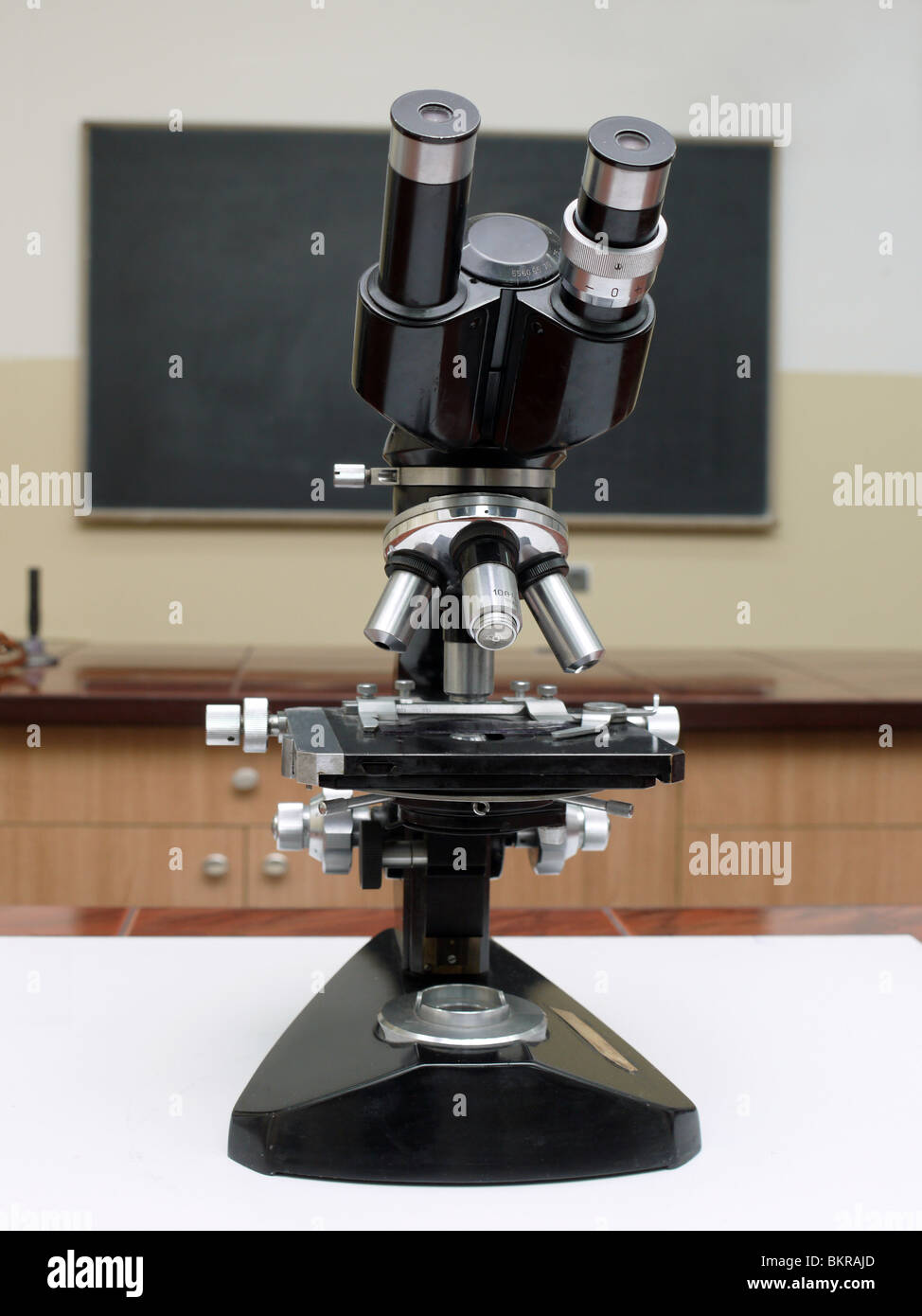 Old school microscope in classroom with blackboard in the background Stock Photo