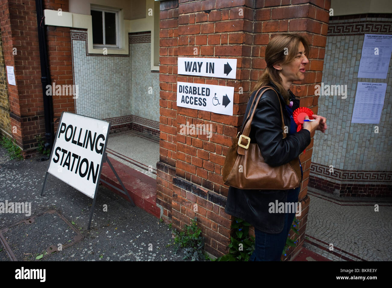 A teller attaches her red Labour Party rosette at the polling station on Britain's general election day Stock Photo