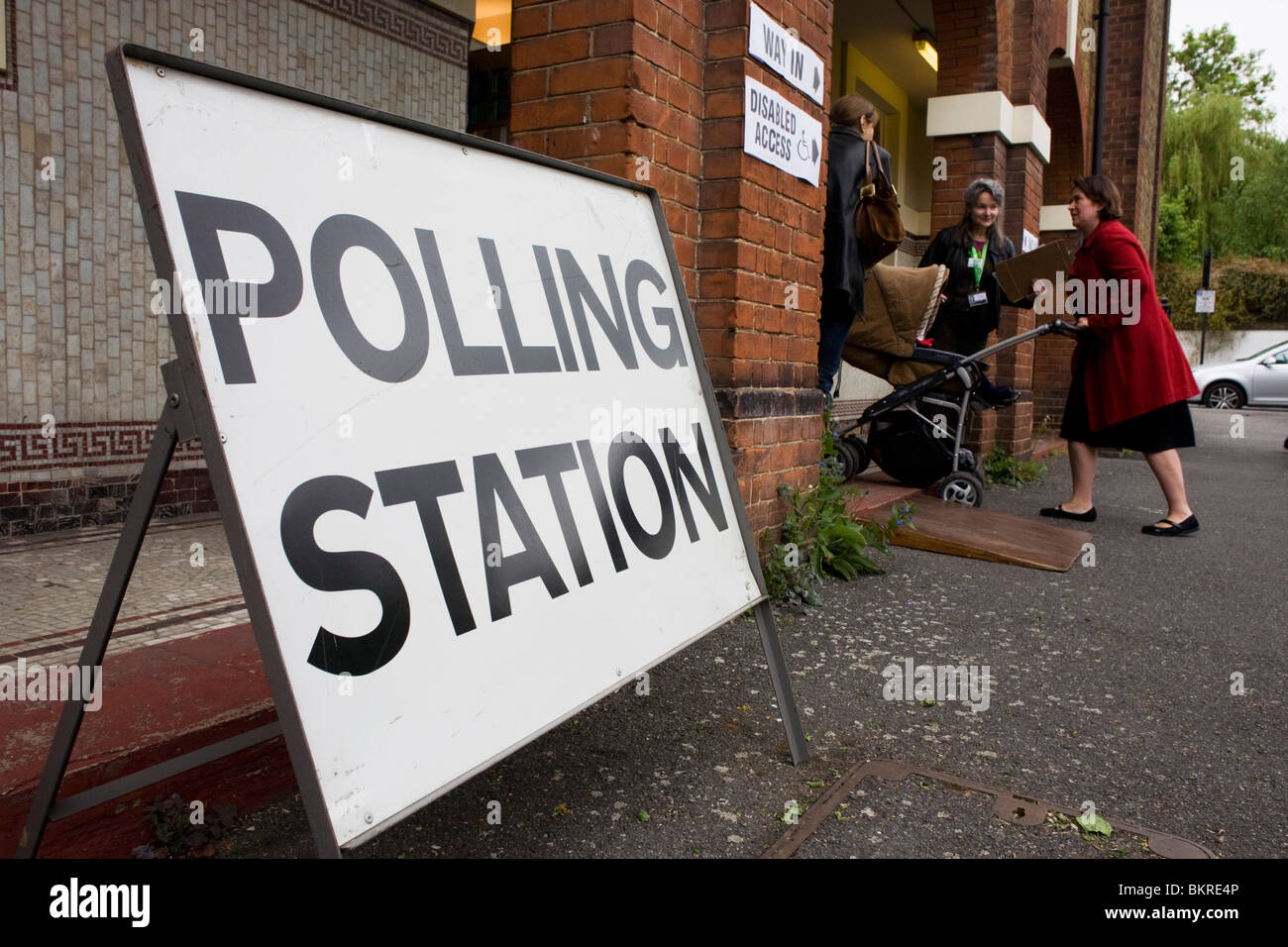 A mother pushes her child into the local polling station on election day. Stock Photo