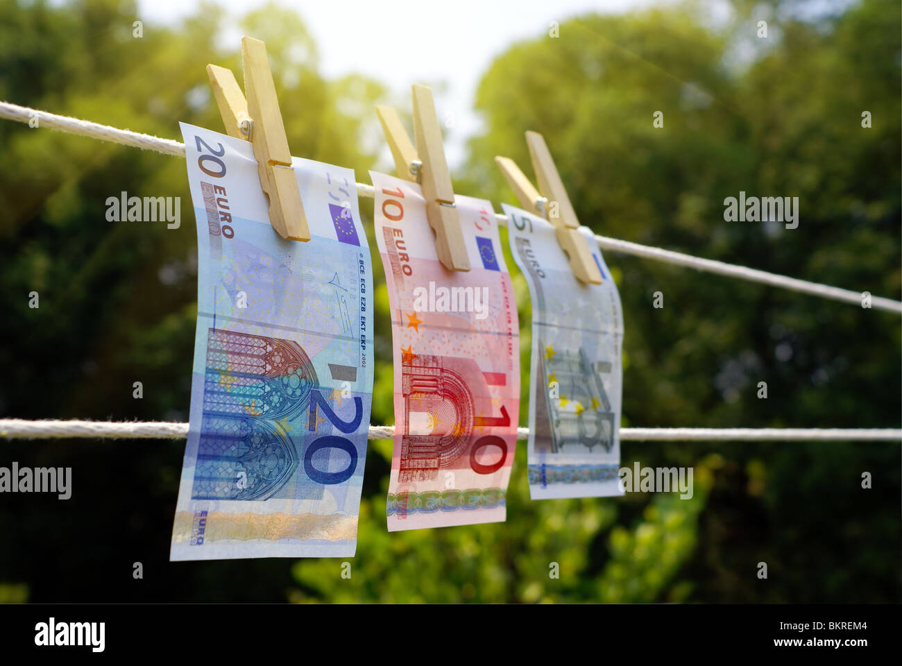 Three Euro bills hanging on a clothes line with wooden clothes pins, symbolizing 'money laundry'. Focus on the 20 Euro bill. Stock Photo