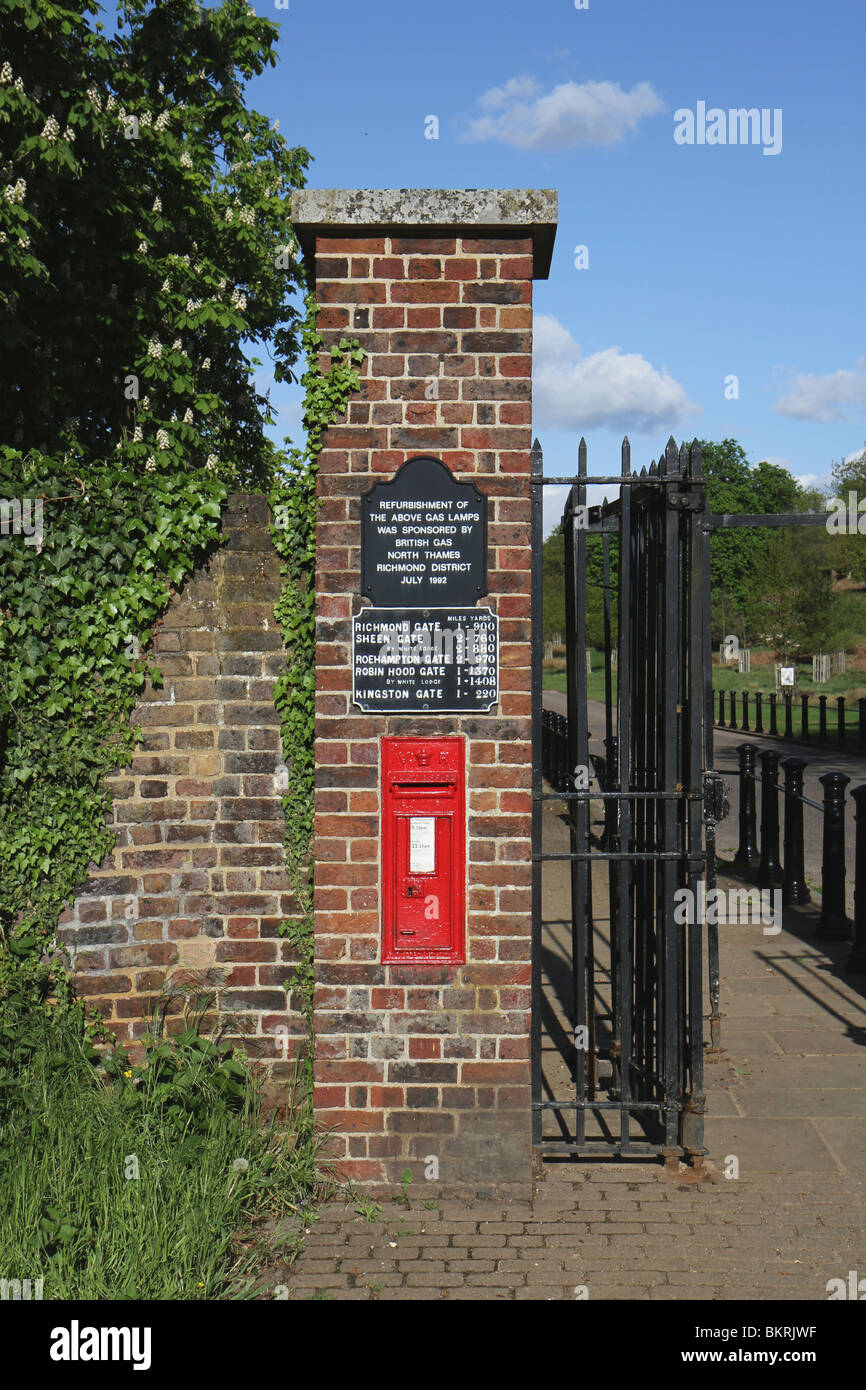 Ham Gate to Richmond Park in Kingston upon Thames. The brick pillar has a red Royal Mail Post box and several signs Stock Photo