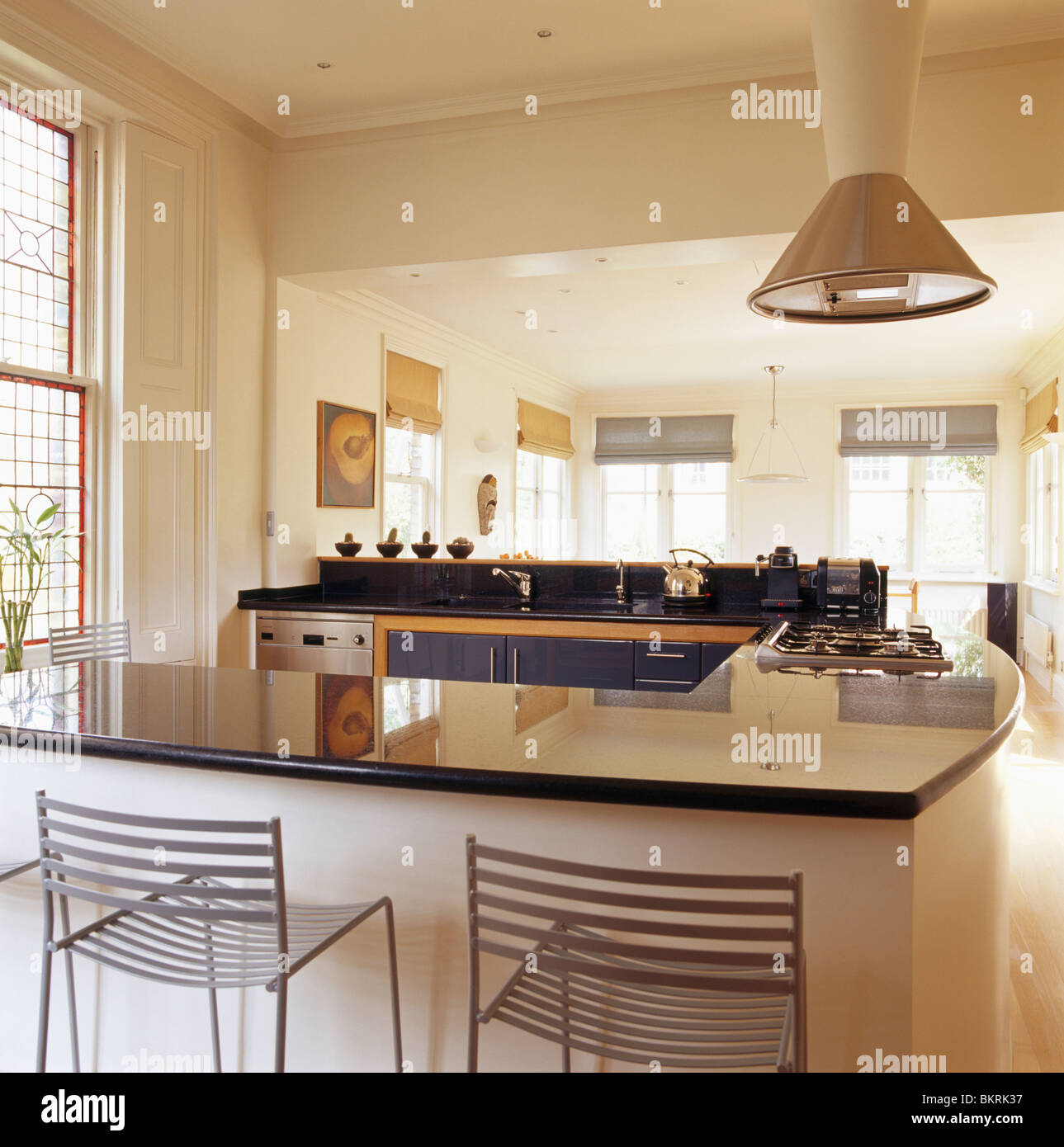 Metal stools at breakfast bar with granite worktop in modern openplan