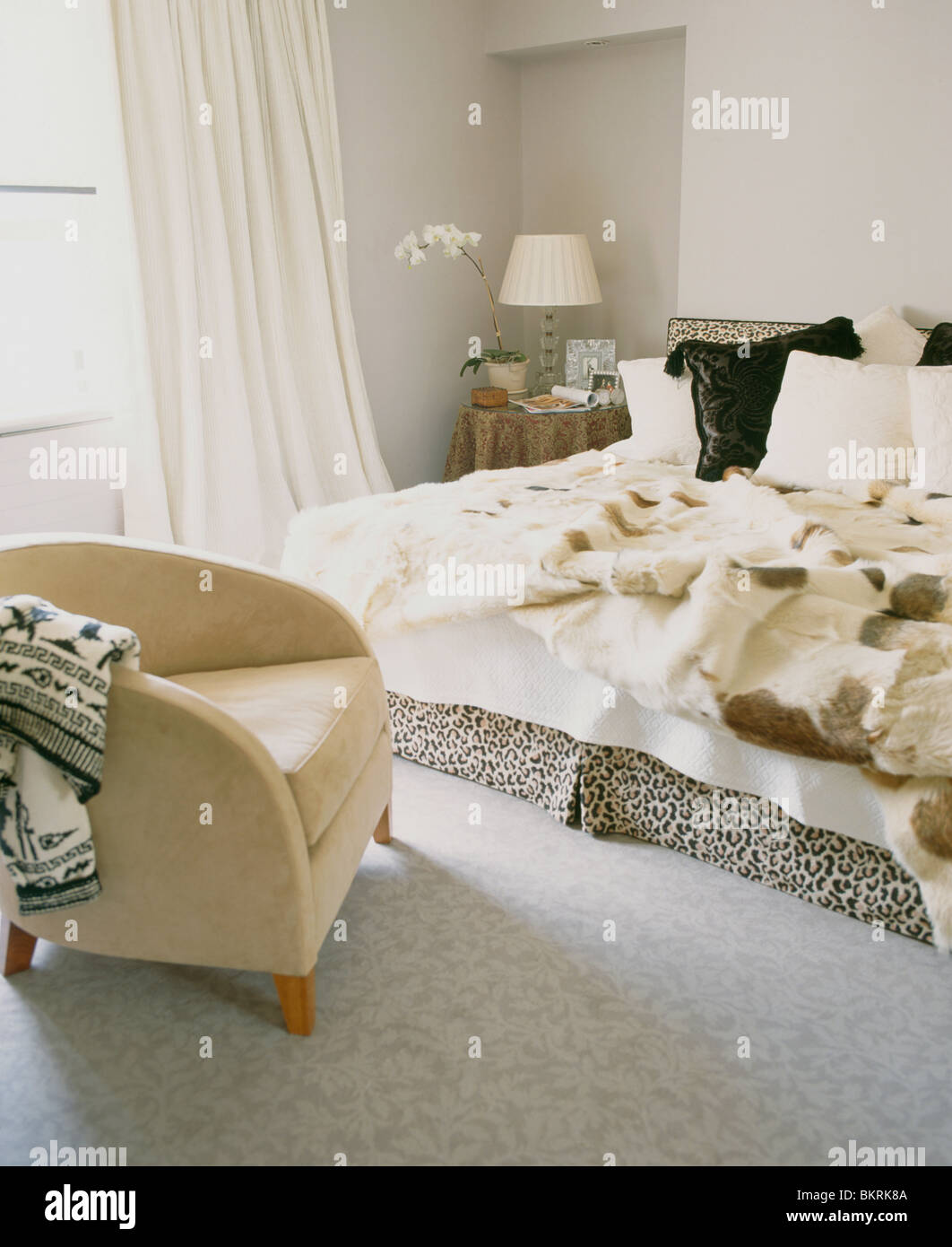 Cream tubchair and grey carpet in modern townhouse bedroom with faux