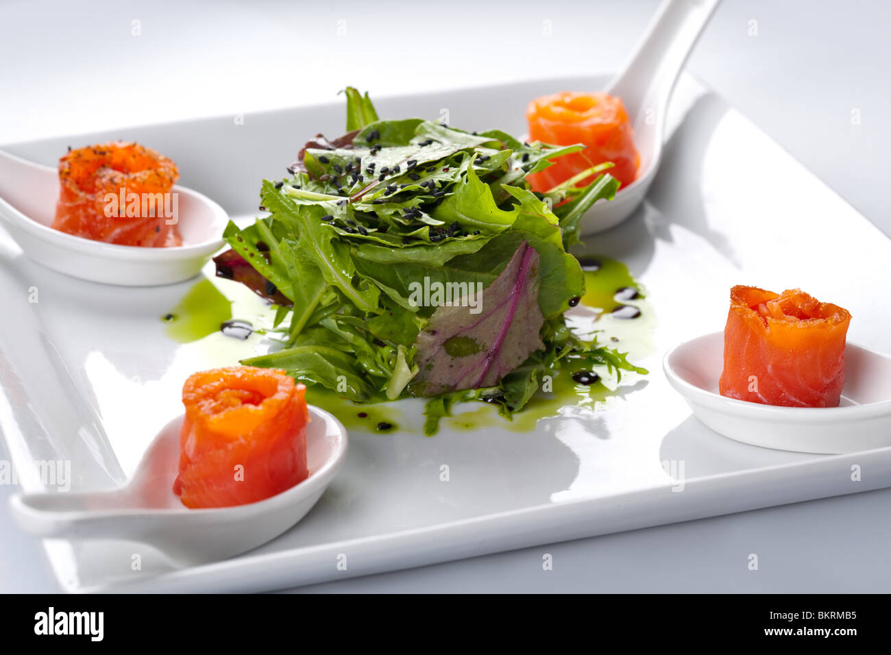 Salmon in a white plate. In the middle of rucola salad. Stock Photo