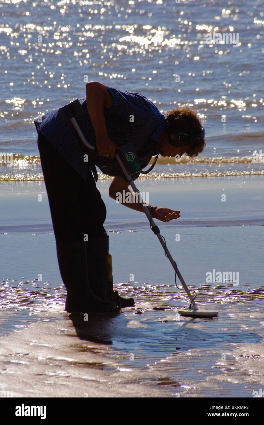 Metal detector user examines a find on beach at Blackpool, England
