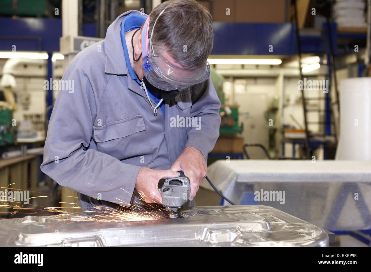 factory floor worker using a angle grinder on metal surface Stock Photo
