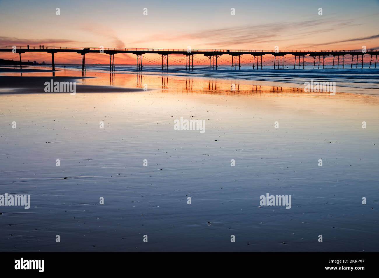 A view of the sun setting behind Saltburn pier on a warm summer's evening Stock Photo