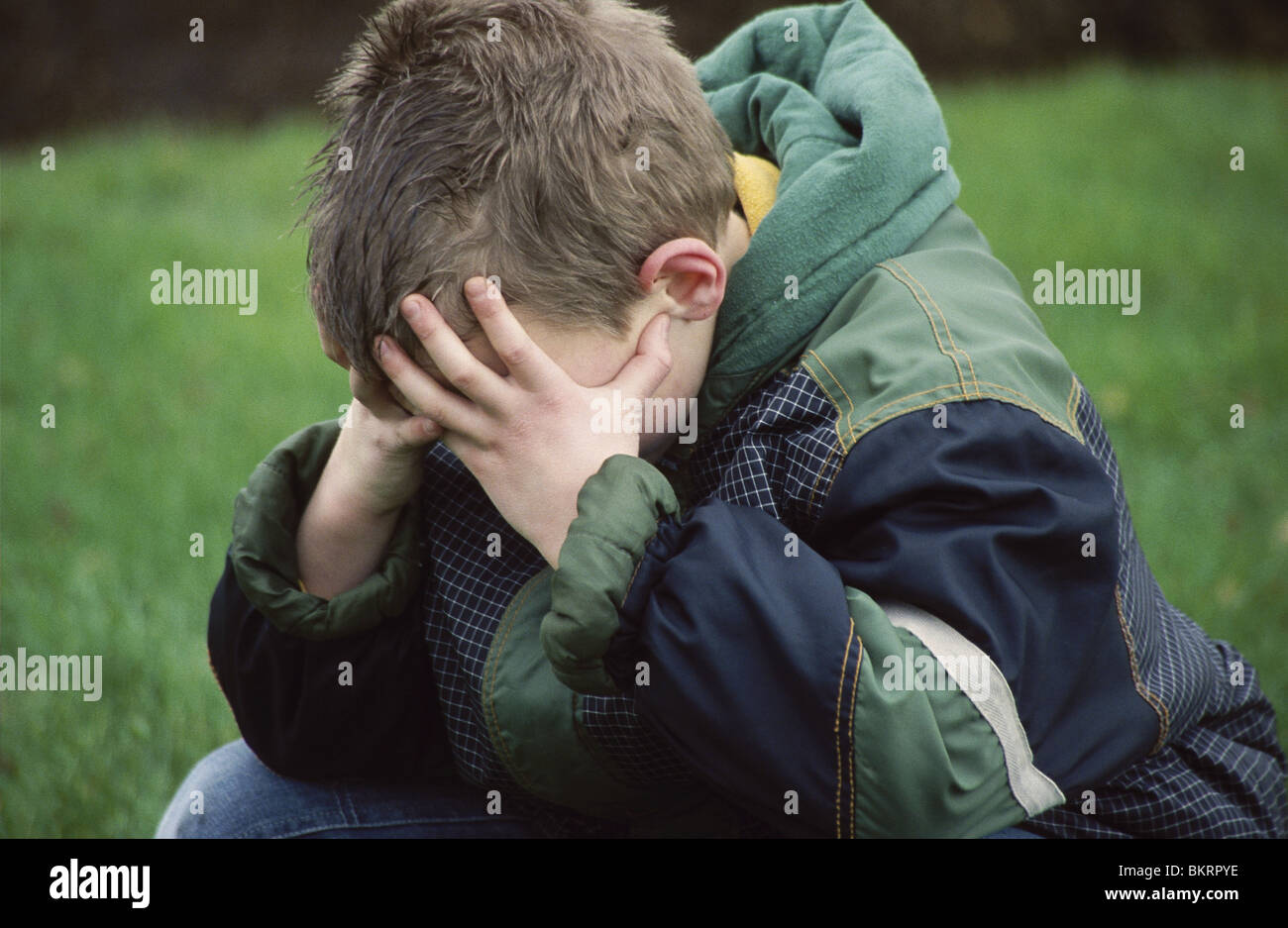 Boyish girl being depressed and lonely and hiding face outside. Stock Photo