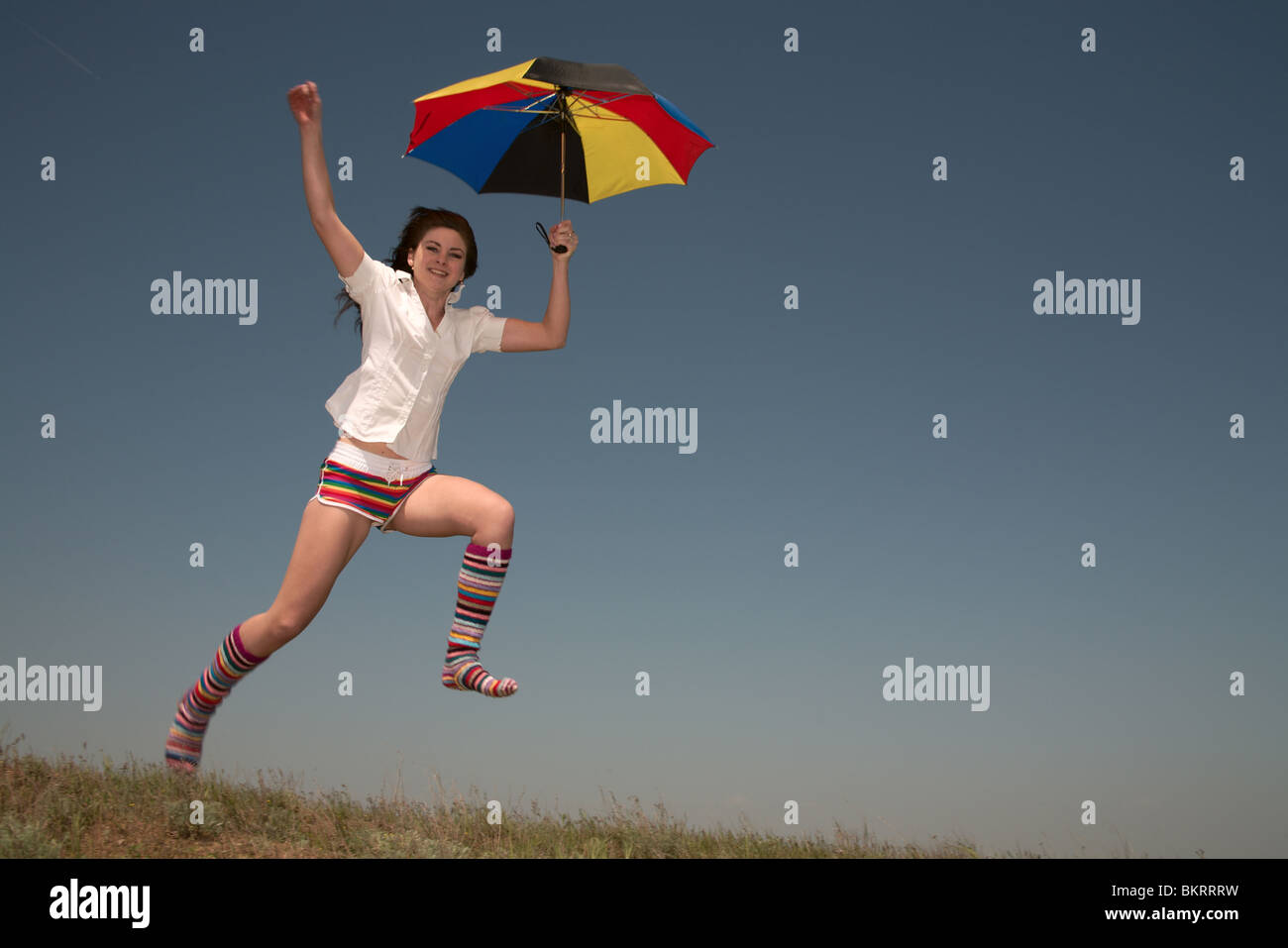 Girl with a color umbrella jumps highly upwards Stock Photo - Alamy