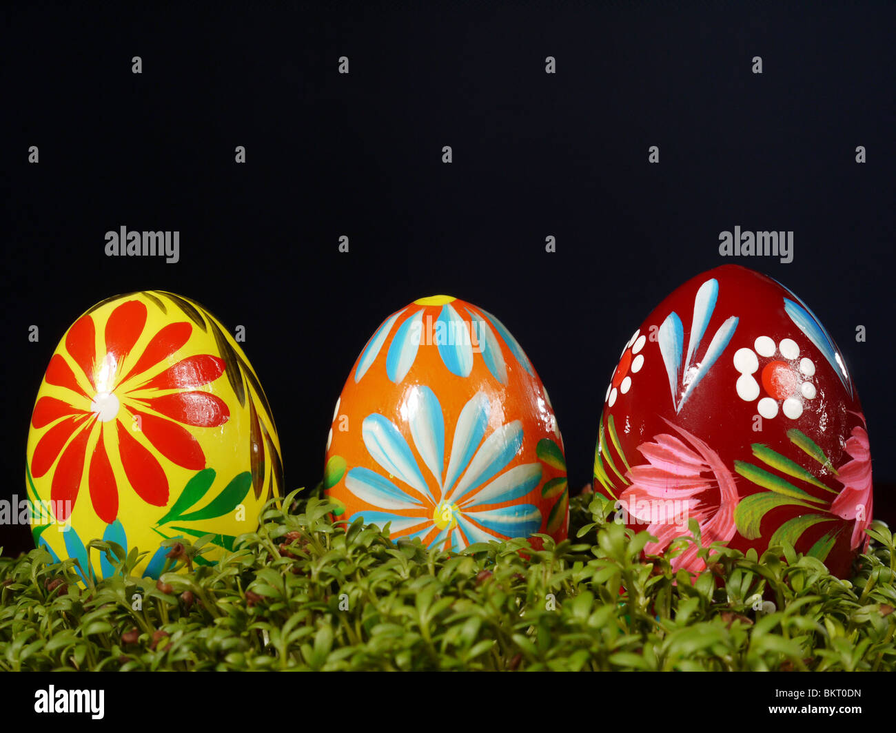 Three painted easter eggs in cress over black background Stock Photo