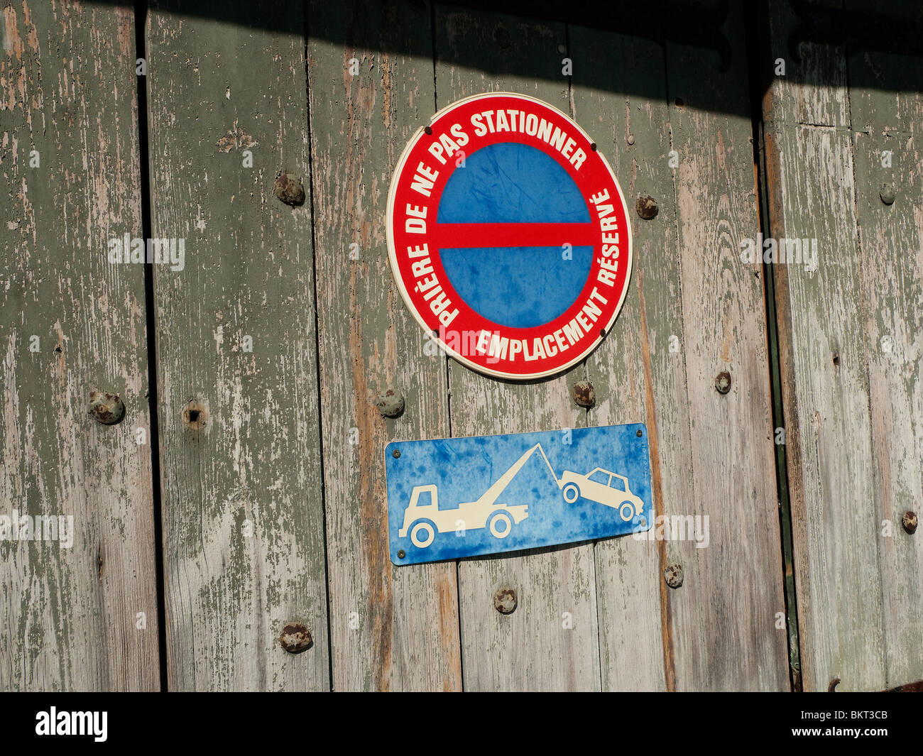 No Parking sign and Tow-away sign on old wood door. Stock Photo
