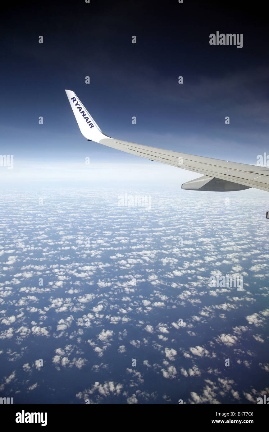 Ryanair plane wing flying over clouds and blue sky Stock Photo