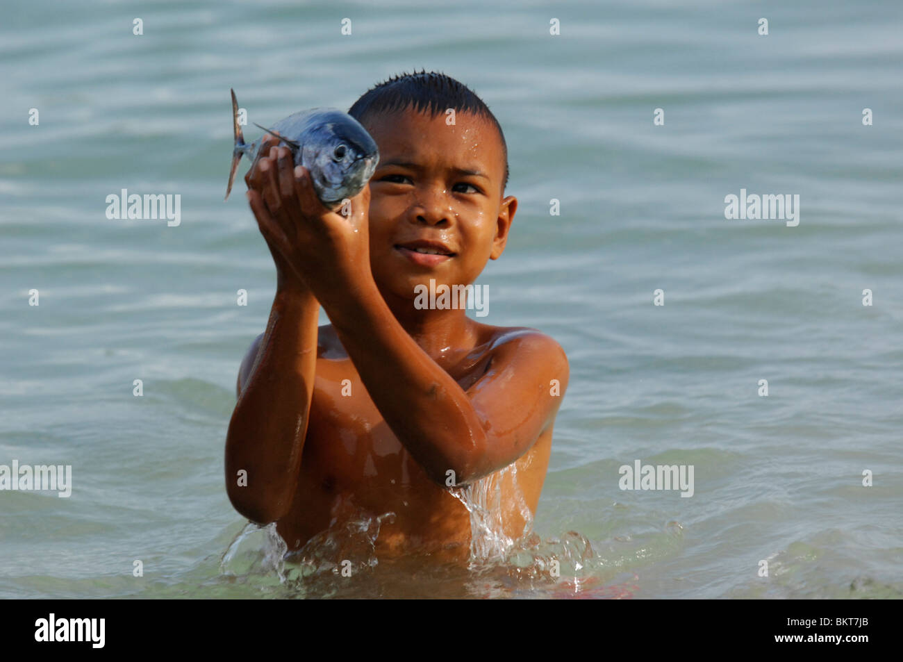 young sea gypsy boy holding fish, chao leh, sea gypsy village , rawai beach , phuket island ,thailand Stock Photo