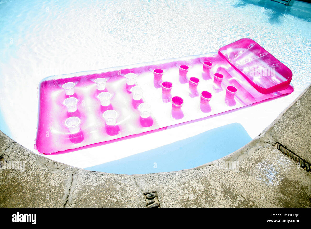 Pink airbed in a swimming pool Stock Photo