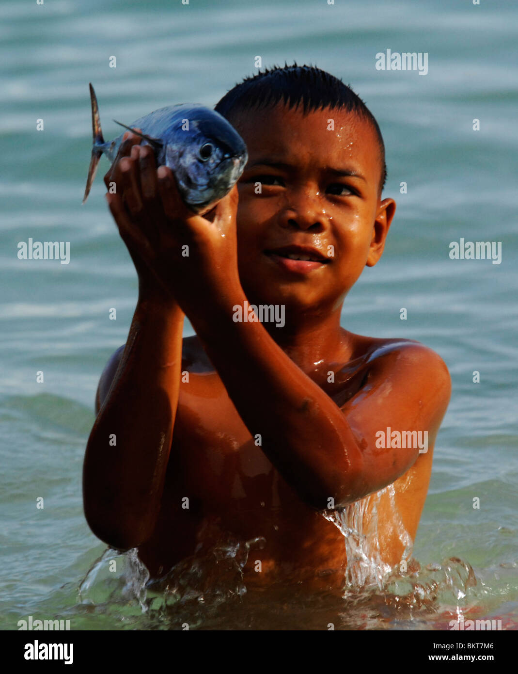 young sea gypsy boy holding fish, chao leh, sea gypsy village , rawai beach , phuket island ,thailand Stock Photo
