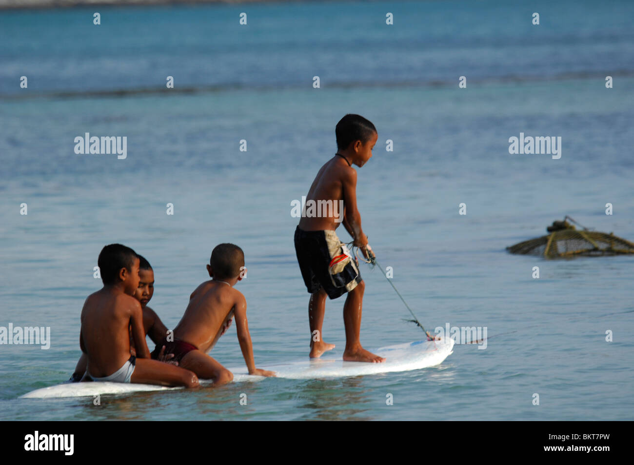 young boys on a surfboard , chao leh, sea gypsy village , rawai beach , phuket island ,thailand Stock Photo