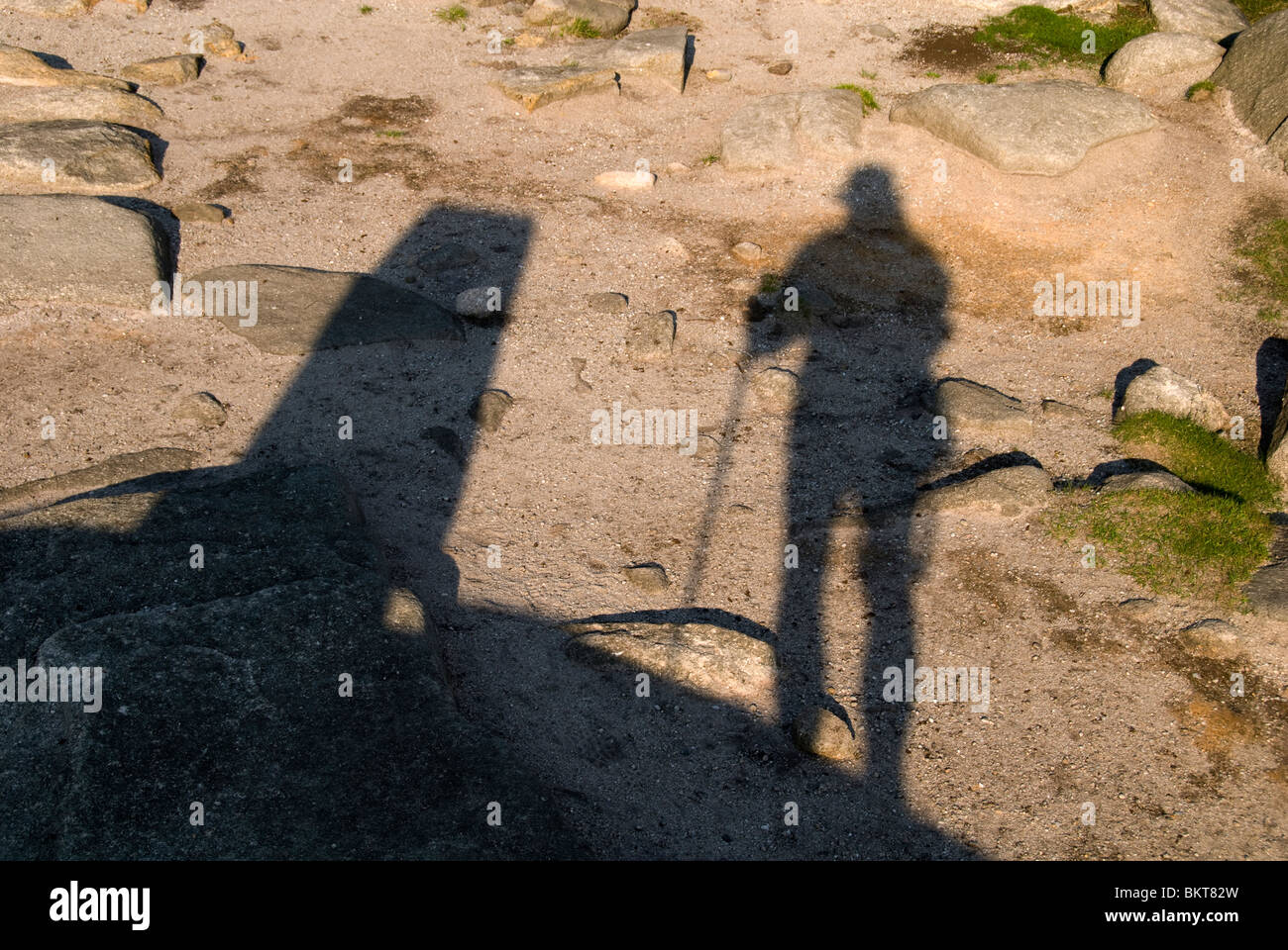 Shadows of a walker and an Ordnance Survey trig point on the Kinder Scout plateau, Hayfield, Peak District, Derbyshire, England UK Stock Photo