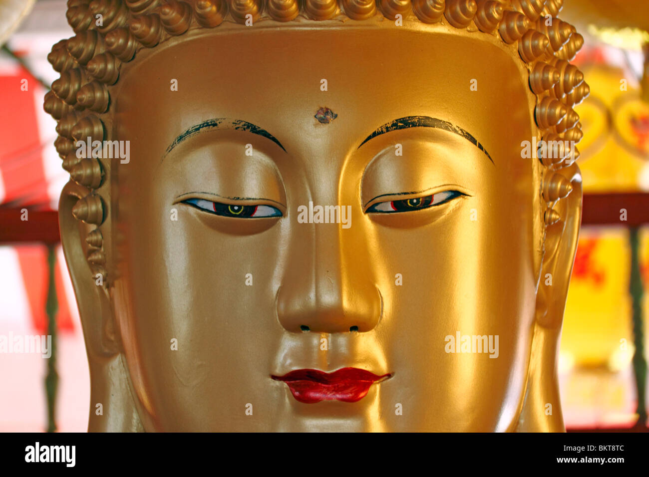 A close-up image of the face of a golden Buddha statue. Stock Photo