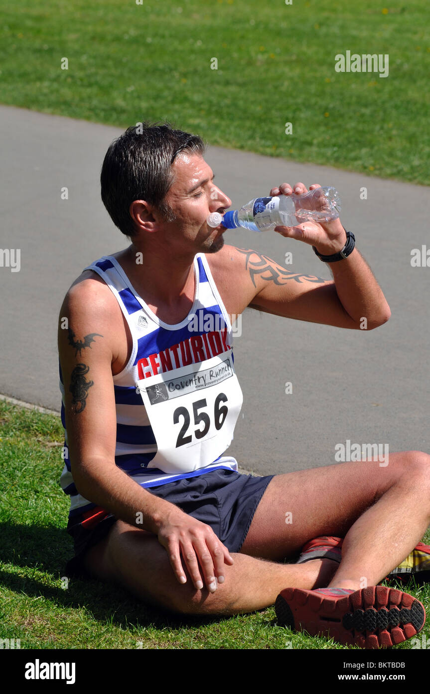 Runner drinking bottled water after a road race Stock Photo Alamy