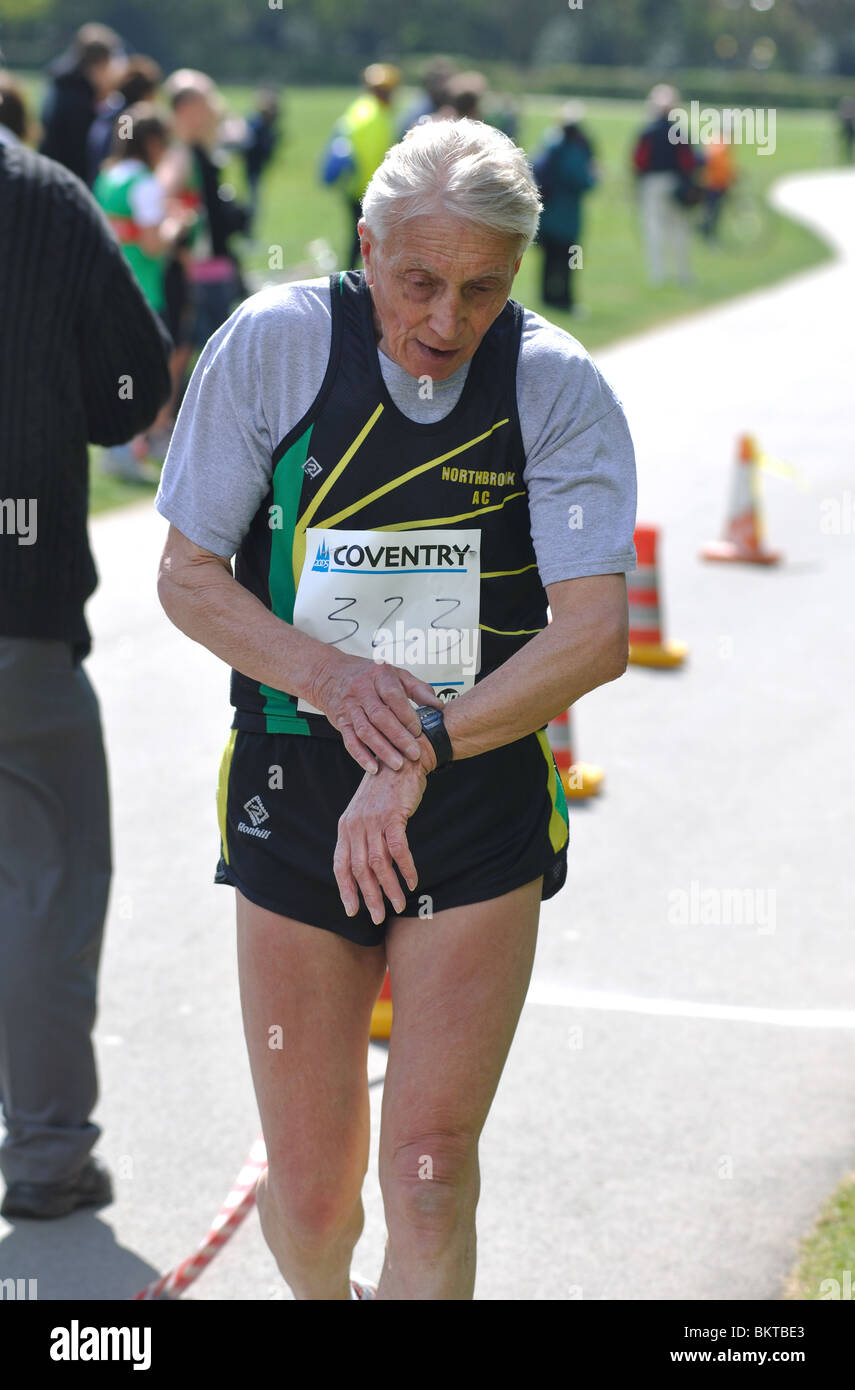 An elderly runner stopping his stopwatch at the end of a road race Stock Photo