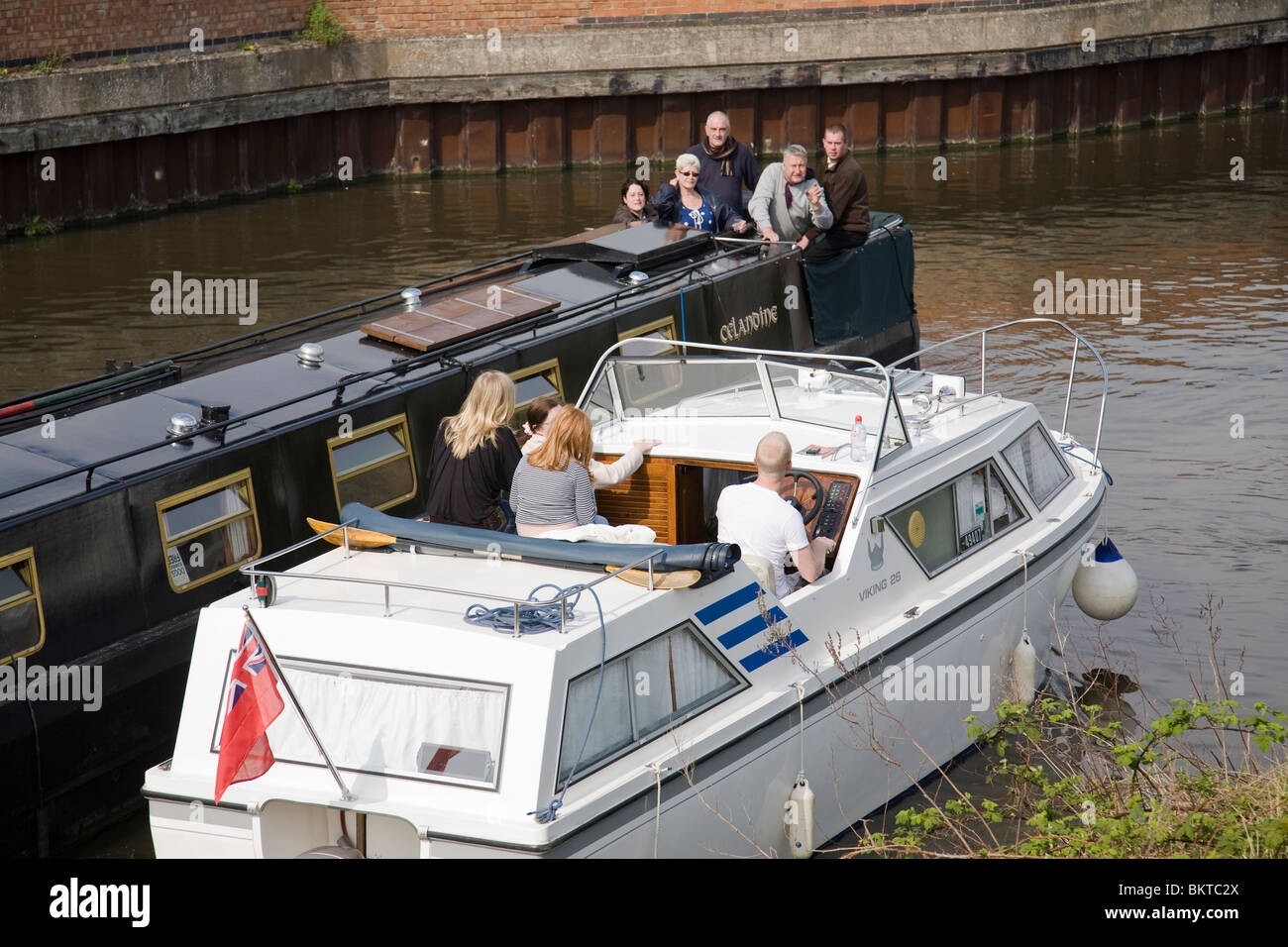 A Narrow Boat And Cabin Cruiser Pass Closely At A Junction On The
