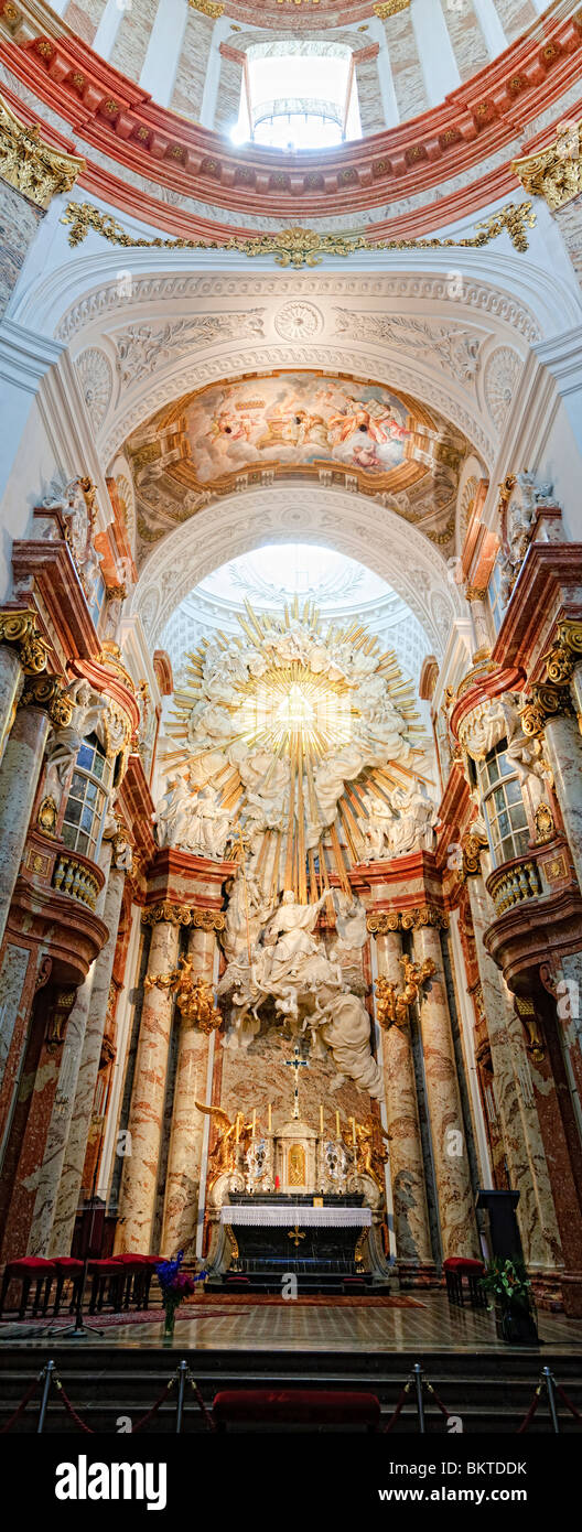 VIENNA, Austria — A high-resolution vertical panorama of the main altar of Karlskirche in Vienna. Karlskirche, or St. Charles's Church, stands tall against the Viennese skyline with its distinct green dome and two flanking columns. The church, an exemplary work of Baroque architecture, was constructed in the early 18th century and is dedicated to Saint Charles Borromeo, a figure known for his dedication to the sick during the time of plague. Stock Photo