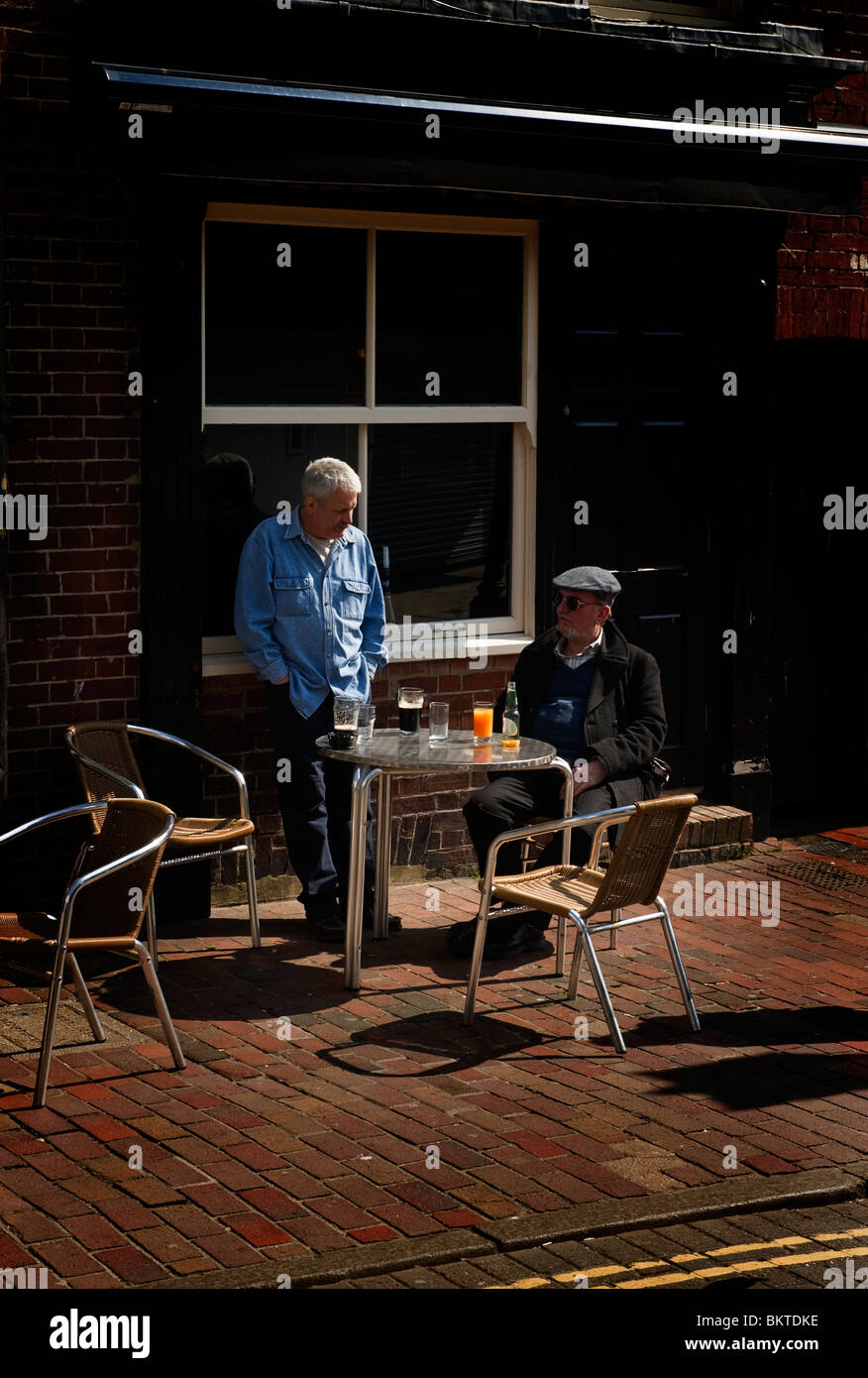 Two middle aged male adult men sitting at table and chairs outside a Brighton pub Stock Photo