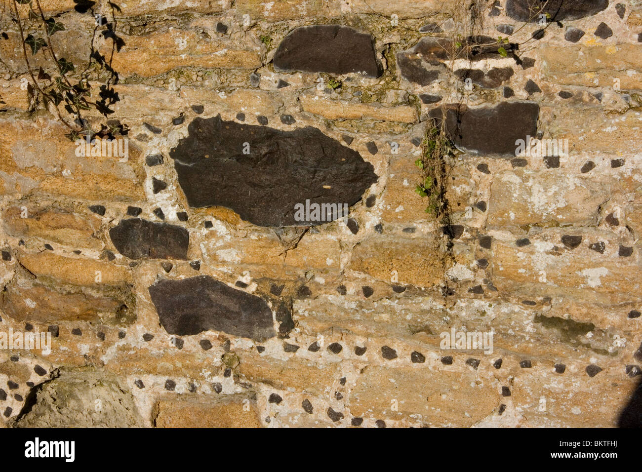 Stone wall with some black sandstone rocks and small decorative chippings in the mortar Stock Photo