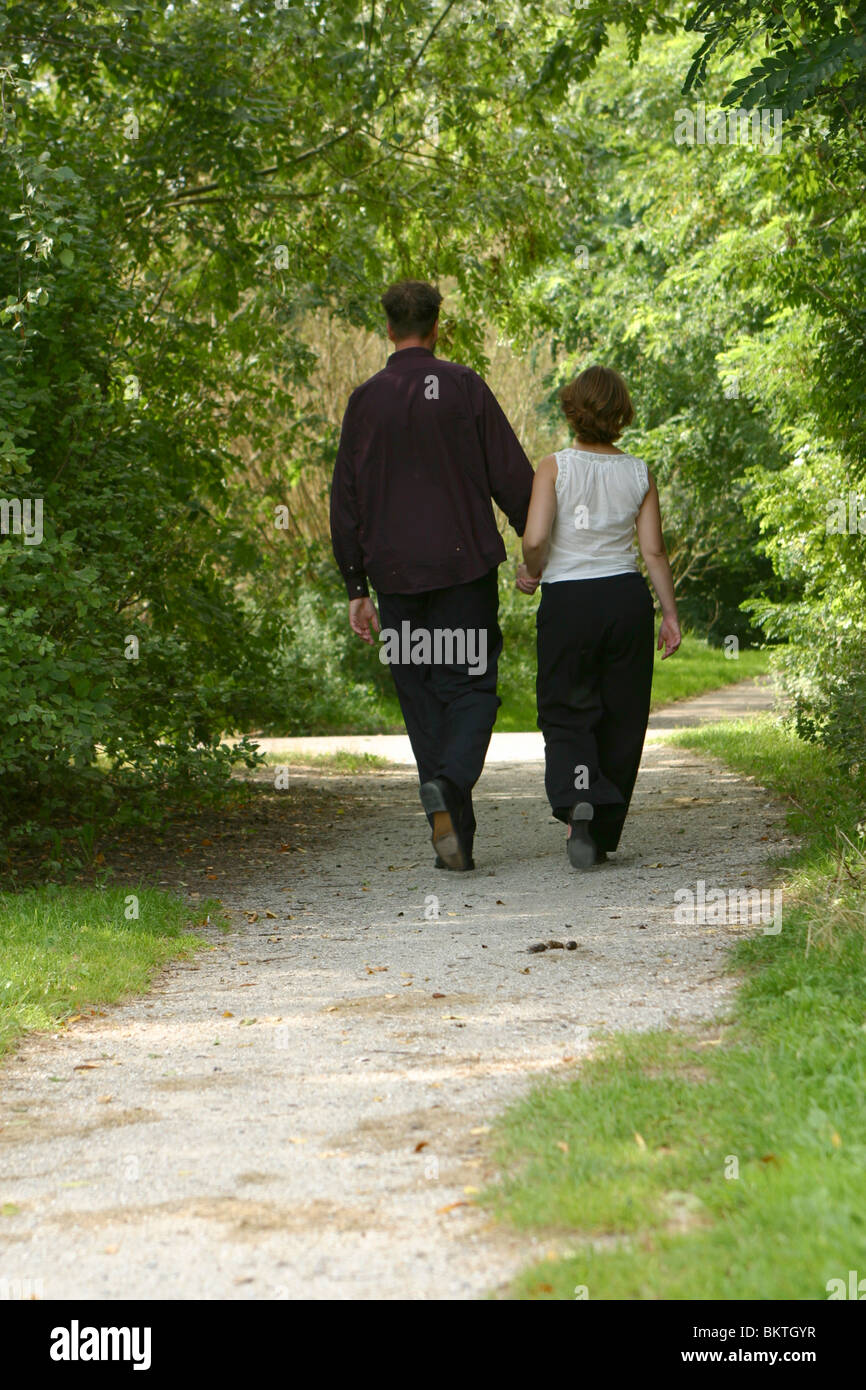 Couple enjoy nature and walk intimate in Forrest together holding hands, third  trimester pregnancy Stock Photo - Alamy