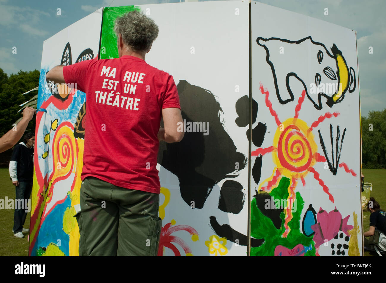 Celebration of World "Fair Trade" Day, with Man Painting Wall, on Lawn of La Villette Park, to Encourage Purchase Fair Trade, slogans t shirt Stock Photo