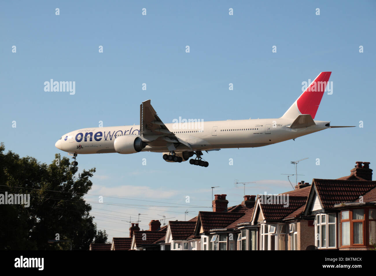 A One World JAL Boeing 777-346/ER landing at Heathrow Airport, London, UK. View from Myrtle Avenue, Hounslow. Stock Photo