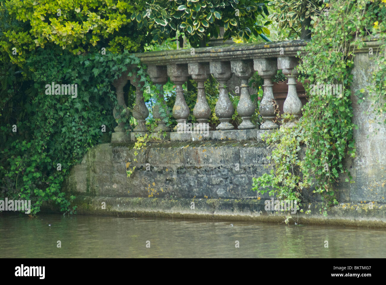 Stone Balustrade by Water with Foliage Stock Photo